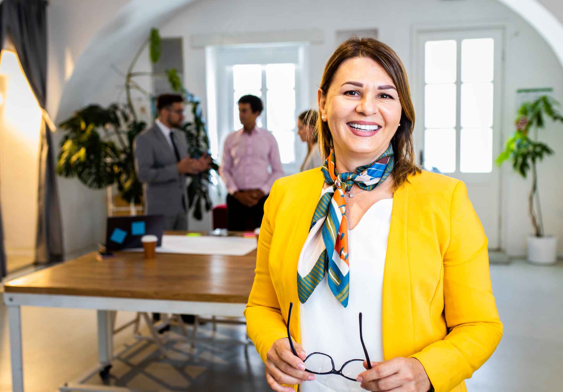 Portrait Of Smiling Businesswoman In Office With Her Colleagues