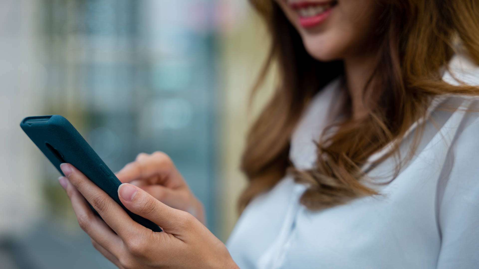 A Woman In A White Shirt Using Her Smartphone For Business