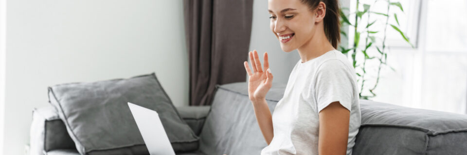 European Smiling Woman Gesturing And Sing Laptop While Sitting On Couch